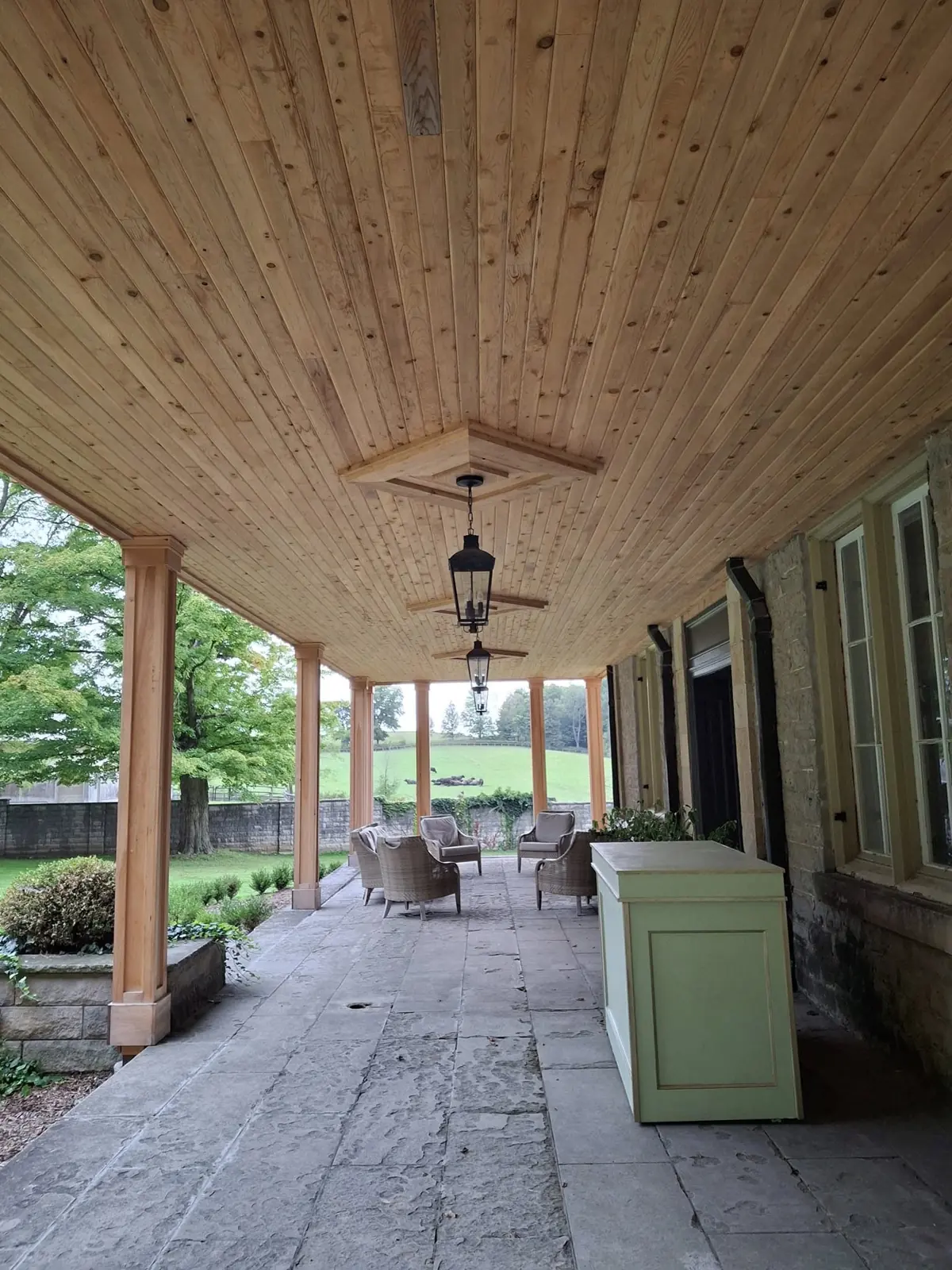 Covered porch with a cedar plank ceiling by AVS Contracting